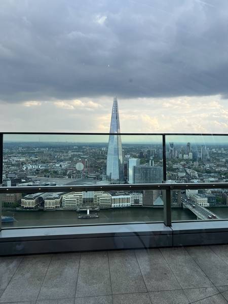 스카이 가든 유리창 너머로 보이는 The Shard. 뾰족한 첨탑이 석양빛 하늘 아래 실루엣으로 보인다