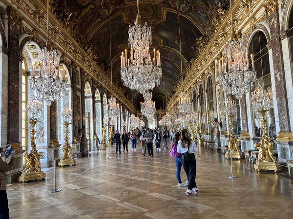 베르사유 궁전의 거울의 방(Galerie des Glaces). 거대한 크리스탈 샹들리에가 줄줄이 매달려 있고, 한쪽은 거울, 한쪽은 아치형 창문. 금빛 장식과 대리석 바닥
