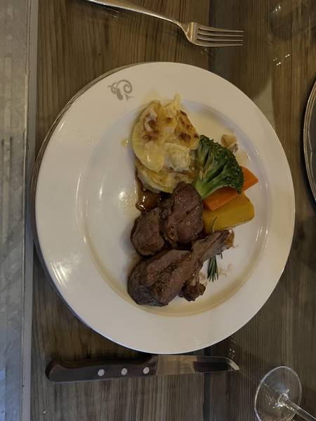 Restaurant Julen에서 먹은 저녁. 하얀 접시 위에 스위스식 고기 요리, 그라탕, 채소(브로콜리, 당근)가 정갈하게 담겨 있다. 와인 잔이 옆에 보인다