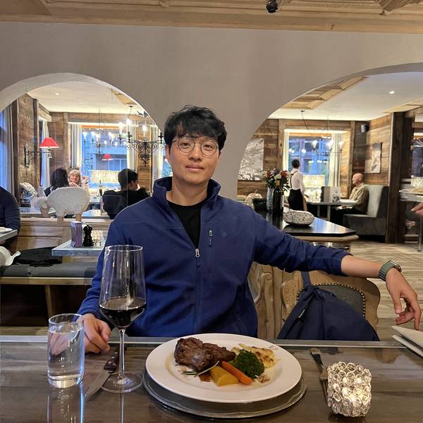 Restaurant Julen 내부에서 포즈. 아치형 천장의 고풍스러운 인테리어. 앞에 고기 요리와 와인이 놓여 있다. 따뜻한 조명